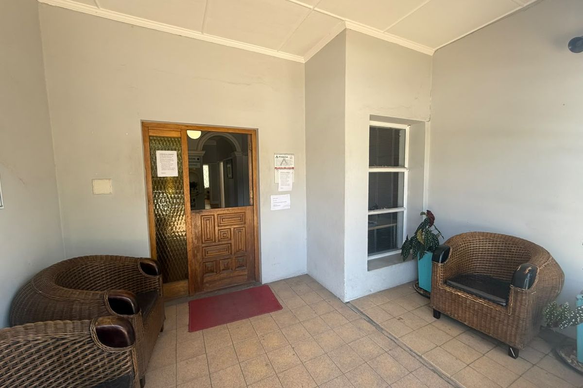 Covered entrance area featuring tiled flooring, a timber panelled door with textured glass, and a fixed window, providing a functional access point to the office.