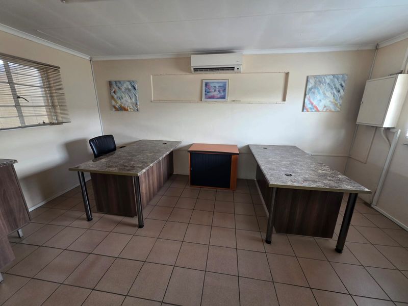 A functional office space featuring tiled flooring, a wall-mounted air conditioning unit, and built-in electrical distribution board.