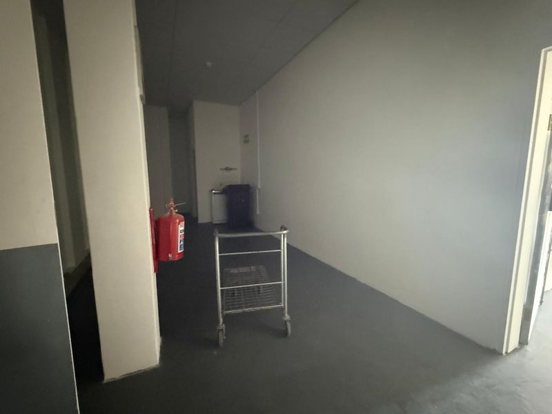A functional utility or storage space featuring painted concrete flooring and a fire safety installation, suitable for various commercial storage or operational needs.