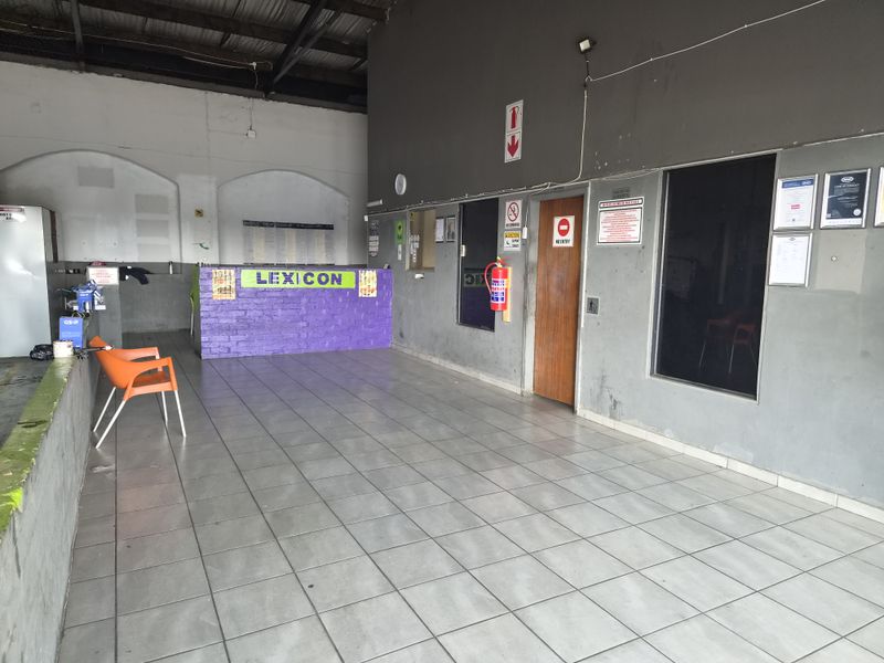 Industrial reception area featuring tiled flooring, an exposed ceiling, and a built-in brick reception counter, providing a functional entry space for the facility.