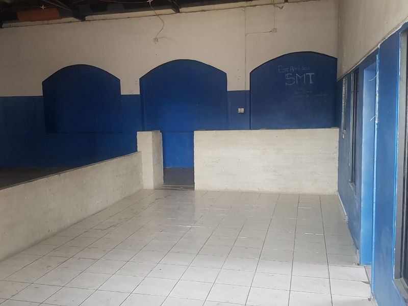 An open-plan industrial space featuring tiled flooring, exposed ceiling structure, and partitioned wall sections, suitable for various commercial or workshop applications.