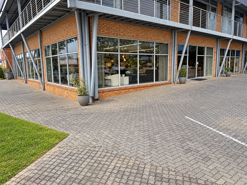 Modern commercial retail building featuring a brick facade, large glass storefront windows, and a paved exterior approach.
