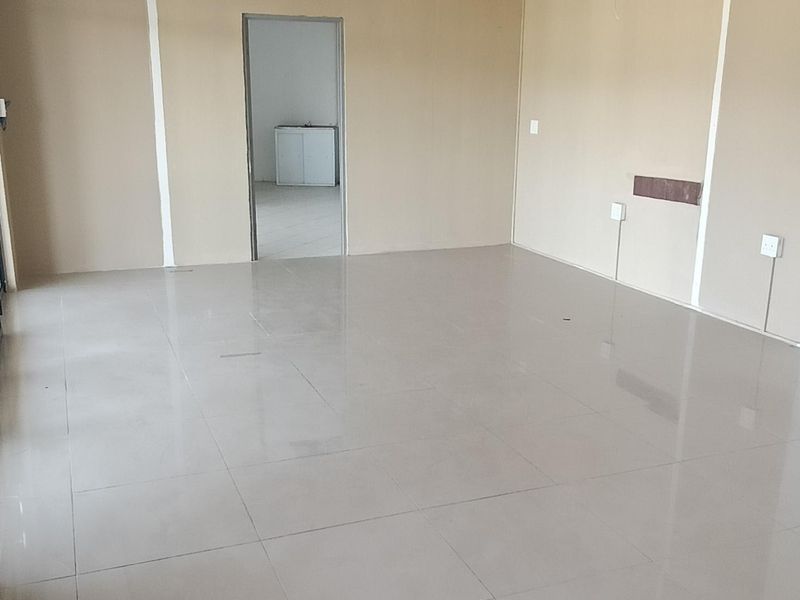 An empty, open-plan retail space featuring ceramic floor tiles, a suspended ceiling, and neutral wall finishes, suitable for various commercial business applications.