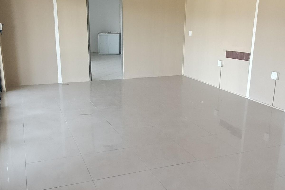 An empty, open-plan retail space featuring ceramic floor tiles, a suspended ceiling, and neutral wall finishes, suitable for various commercial business applications.