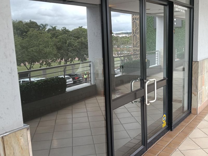Entrance to a retail studio space featuring aluminium framed glass double doors, tiled flooring, and stone cladding accents.