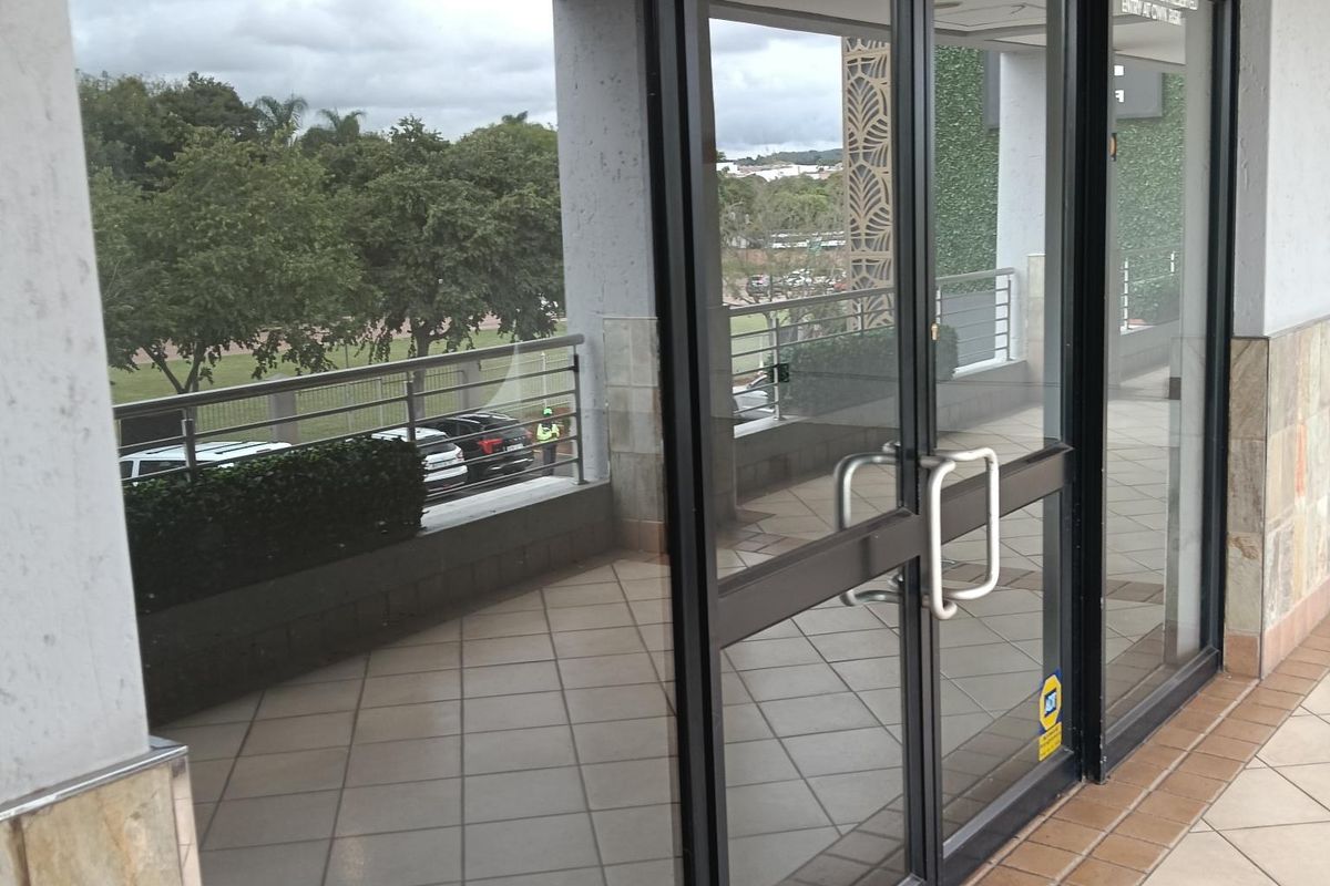 Entrance to a retail studio space featuring aluminium framed glass double doors, tiled flooring, and stone cladding accents.