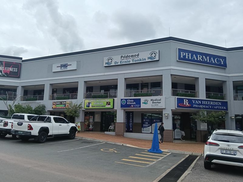 Front elevation of a multi-tenant commercial office and retail complex featuring various business signage and a paved parking area.