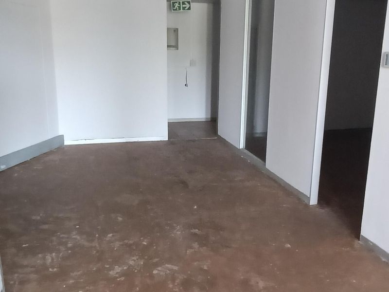 An empty office space featuring a suspended ceiling with recessed lighting and partition walls, currently requiring flooring and wall finish improvements.