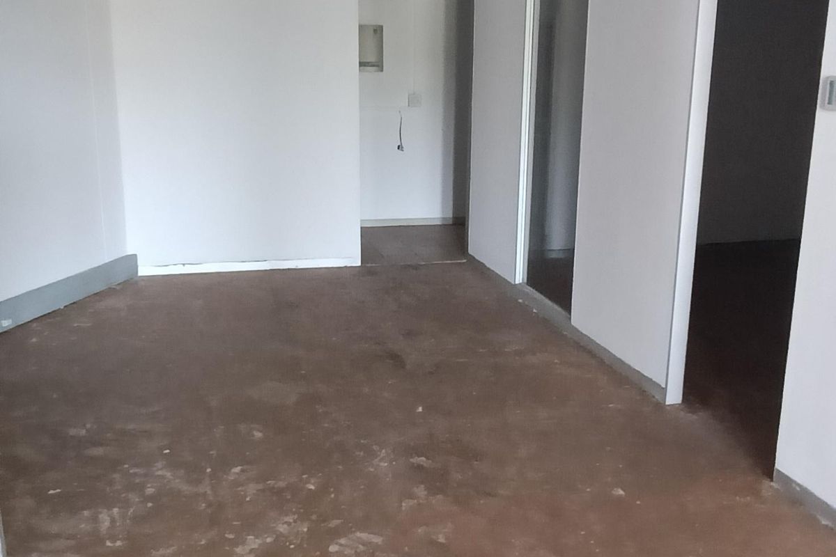 An empty office space featuring a suspended ceiling with recessed lighting and partition walls, currently requiring flooring and wall finish improvements.