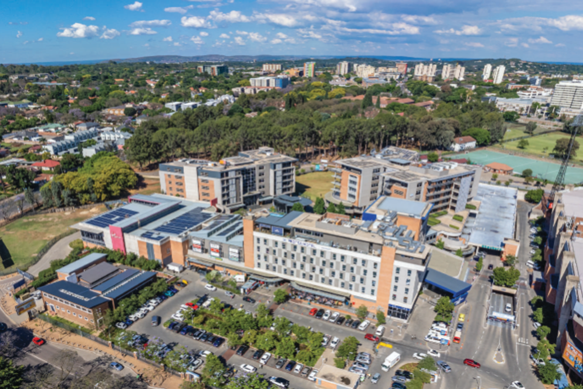 Aerial view of a large commercial office and retail complex featuring extensive parking facilities, solar panel installations, and proximity to a stadium.