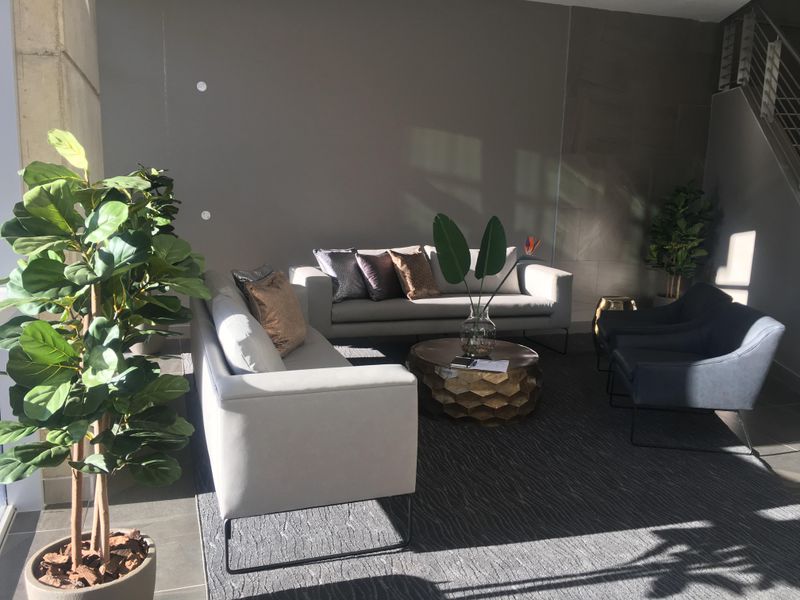 A modern, well-lit office lounge area featuring a staircase and neutral tiled flooring, creating a professional and welcoming reception or waiting space.