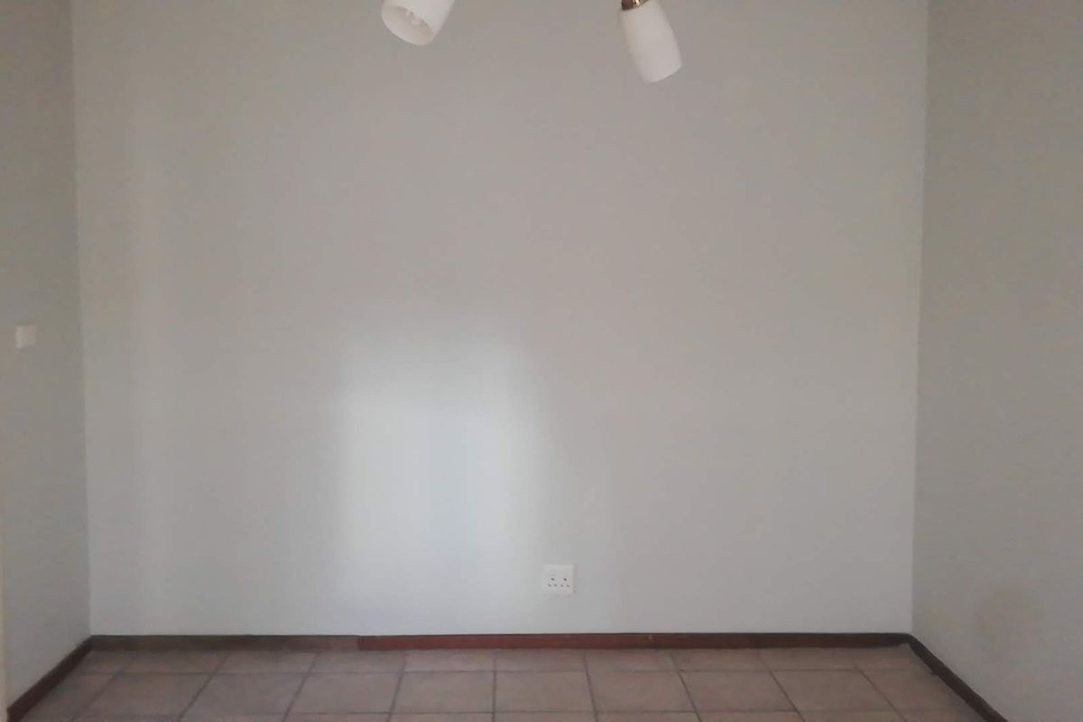 A simple, empty room featuring tiled flooring, neutral walls, and a ceiling-mounted light fixture.