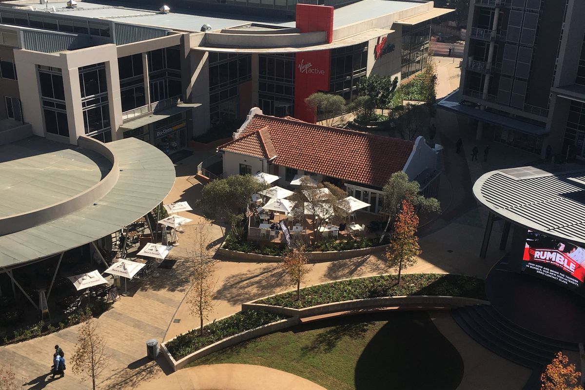 Aerial view of a modern commercial office complex featuring a central water fountain, landscaped courtyards, and integrated outdoor dining spaces.