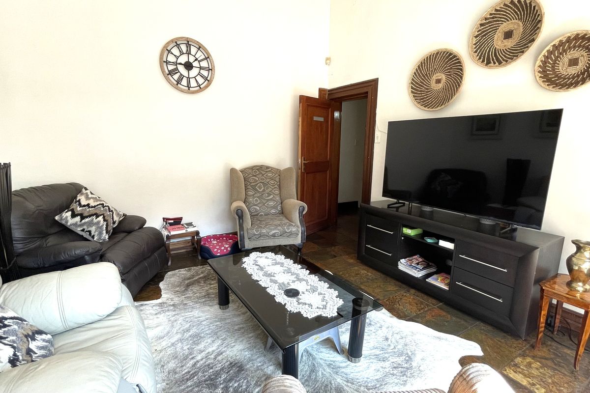 A comfortable living room featuring tiled flooring and a traditional wooden door, providing a functional space for relaxation or client waiting area.