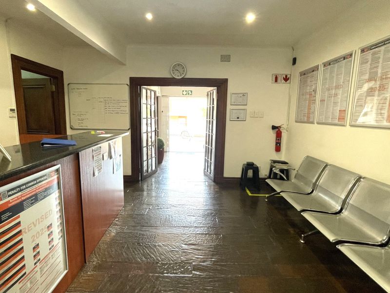 Commercial reception area featuring a built-in service counter, tiled flooring, recessed lighting, and a direct entrance with double glass-paneled doors.