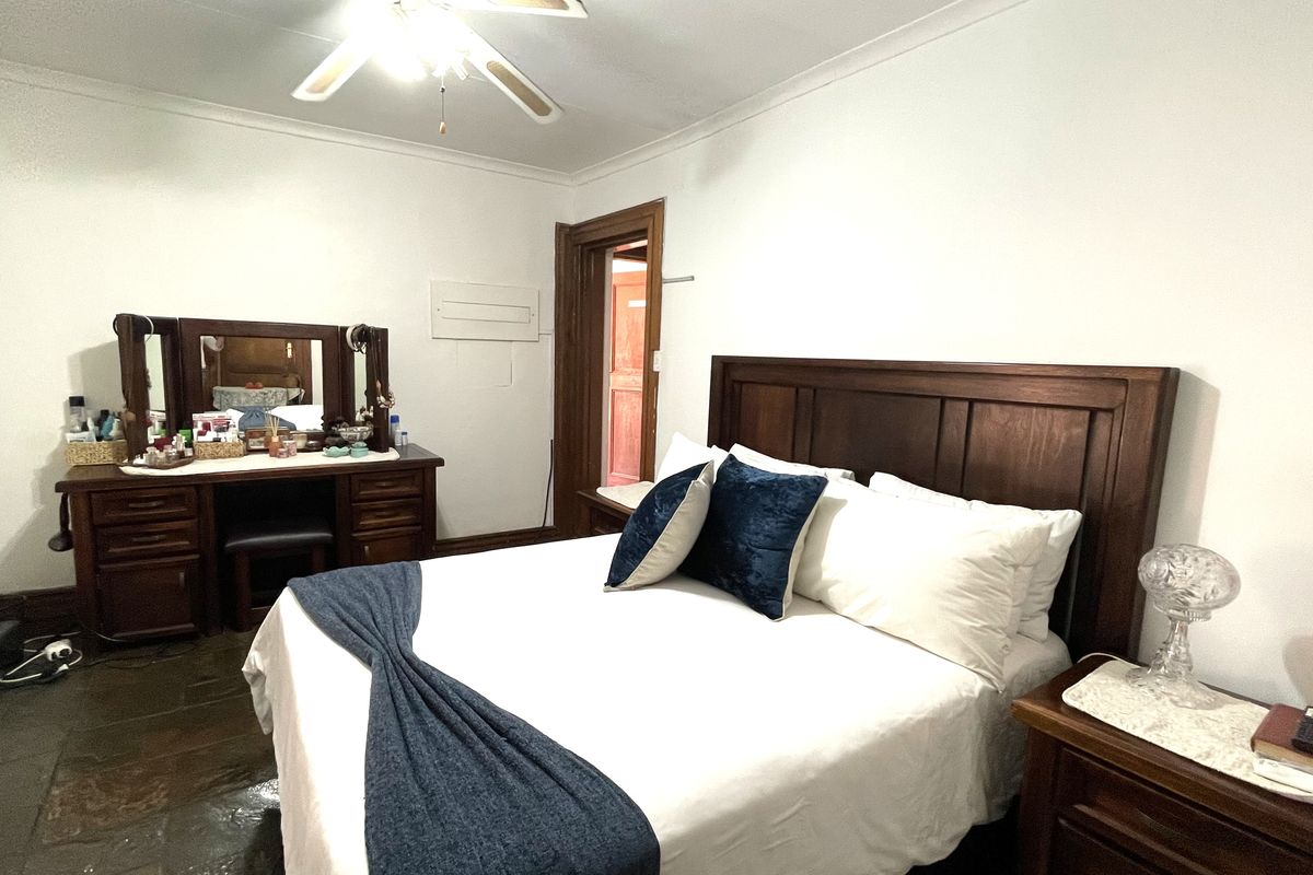 A bedroom featuring a ceiling fan, tiled flooring, and wooden door frames, providing a functional and comfortable living space.