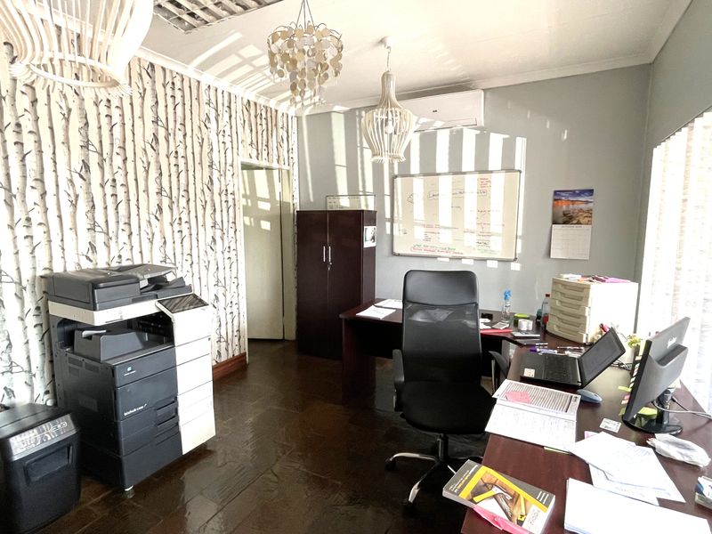 A functional commercial office space featuring patterned wallpaper, a wall-mounted whiteboard, and a split-system air conditioning unit.