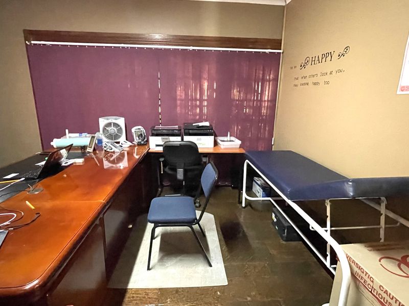 A functional office or consultation room featuring a built-in desk area and tiled flooring, suitable for professional or medical use.
