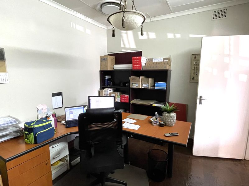 A functional commercial office space featuring a standard door, ceiling-mounted light fixture, and ventilation vent.