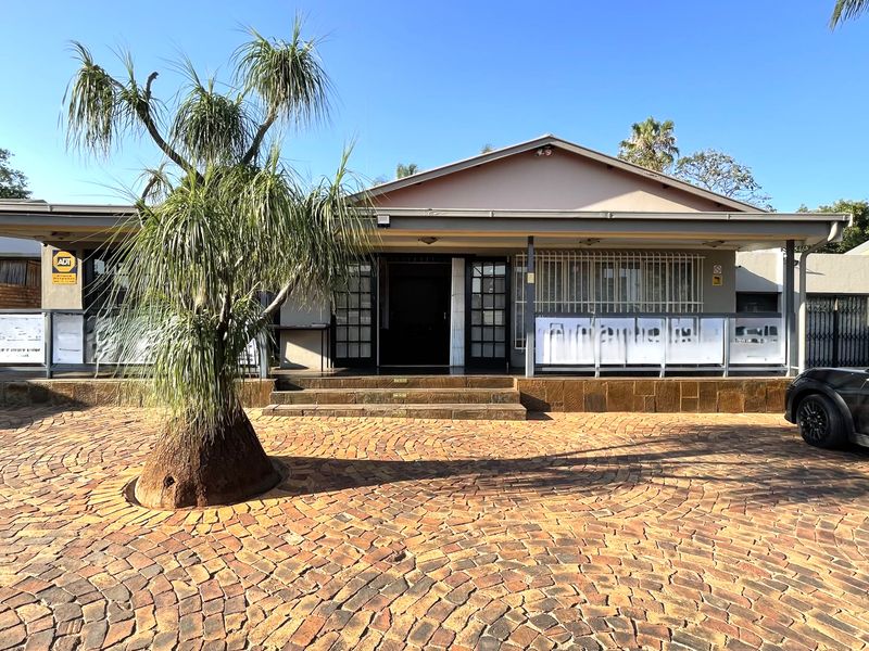 Front elevation of a commercial property featuring a paved driveway, covered entrance porch, and security bars on windows.