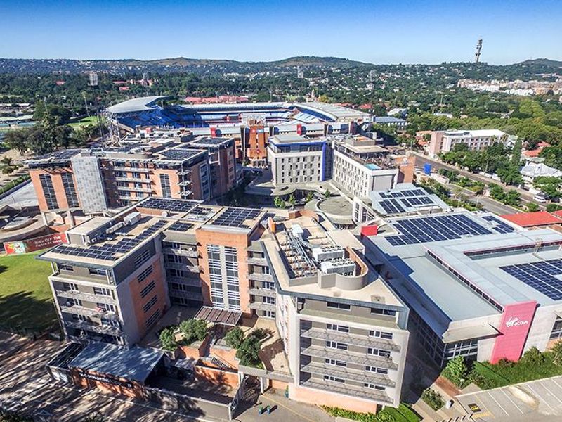 Aerial view of a large office complex featuring multiple buildings with rooftop solar installations, HVAC systems, and surrounding parking facilities.