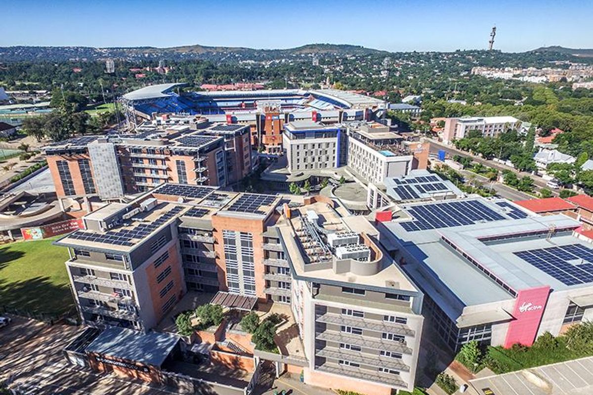 Aerial view of a large office complex featuring multiple buildings with rooftop solar installations, HVAC systems, and surrounding parking facilities.