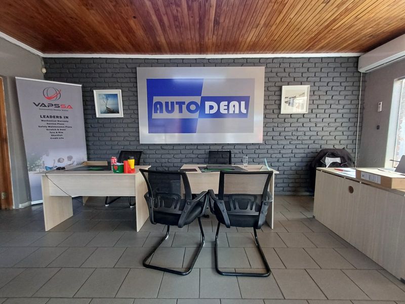 Commercial office space featuring a dark grey brick feature wall, timber-clad ceiling, and tiled flooring, suitable for a professional dealership environment.