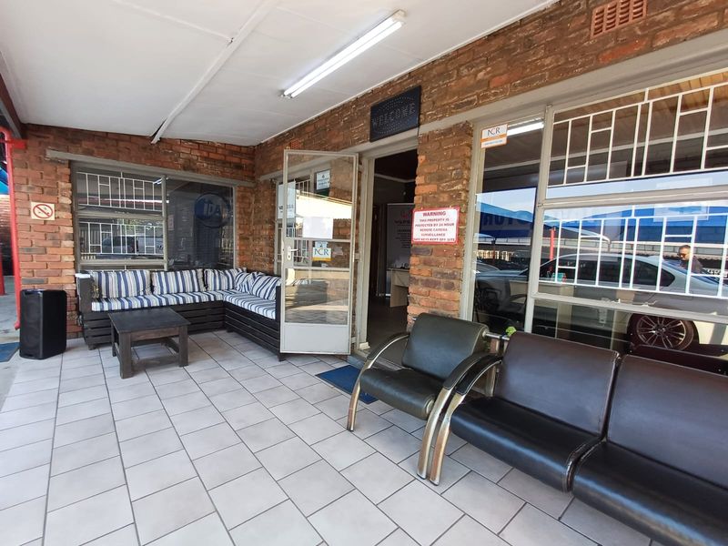 Covered entrance patio featuring exposed brick walls, tiled flooring, and secure metal-framed windows with security bars.