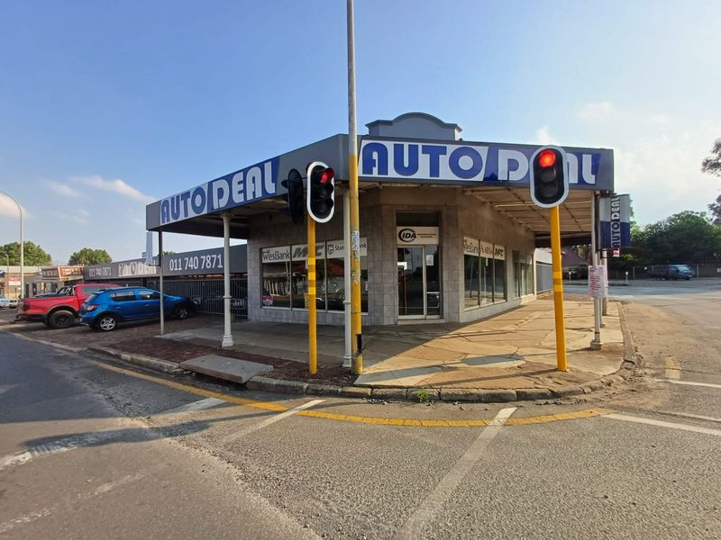Corner commercial property featuring prominent signage, large display windows, and a covered walkway, situated at a high-visibility street intersection.