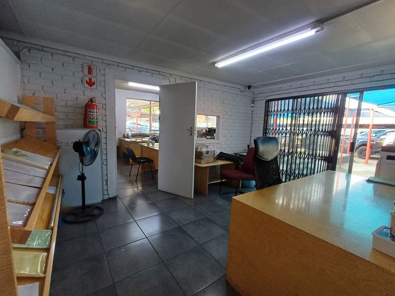 Functional commercial office space featuring tiled flooring, painted brick walls, and a security gate leading to an exterior parking area.