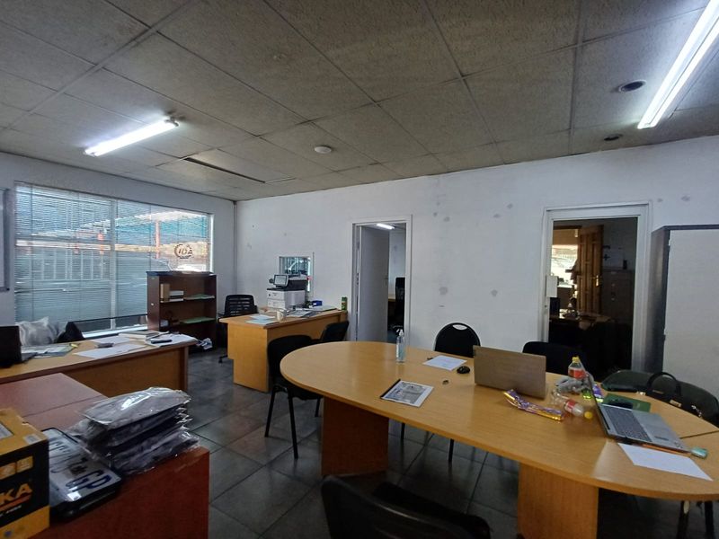 A commercial office space featuring a suspended ceiling, tiled flooring, and multiple doorways leading to adjacent rooms.