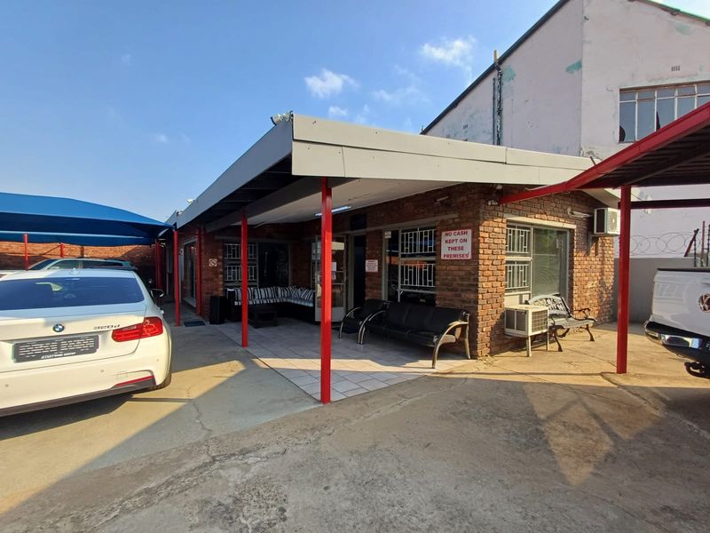 Commercial exterior view featuring a covered patio area with brick facade, tiled flooring, and metal support columns.