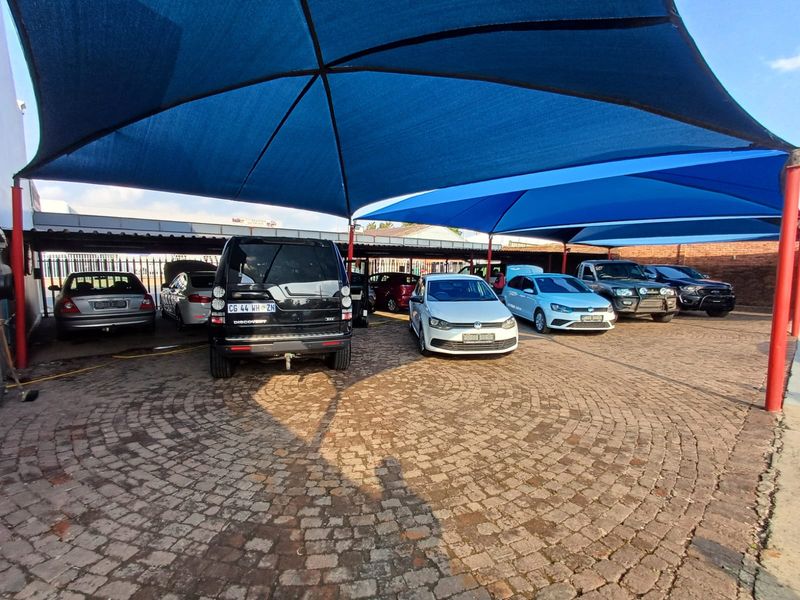 Commercial outdoor parking area featuring extensive blue shade sail structures and durable paved surfacing, suitable for vehicle display or customer parking.