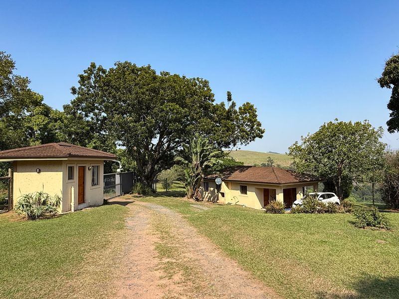 A view of the farm property featuring a detached outbuilding and the main residence set within a spacious, well-maintained garden landscape.