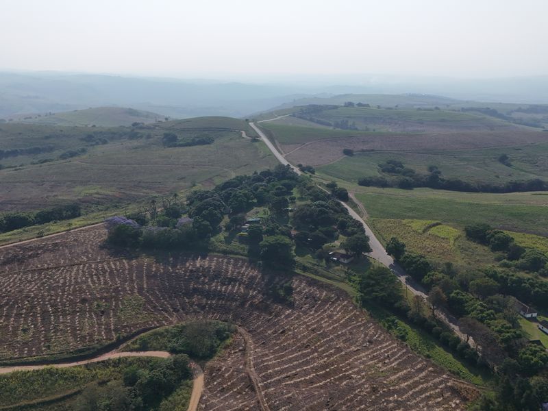 An aerial view of the expansive farm property, showcasing the rolling landscape, agricultural fields, and existing structures nestled among the trees.