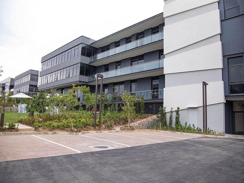 Modern multi-story office building featuring a contemporary facade, glass balcony railings, and well-maintained landscaped grounds with paved parking facilities.