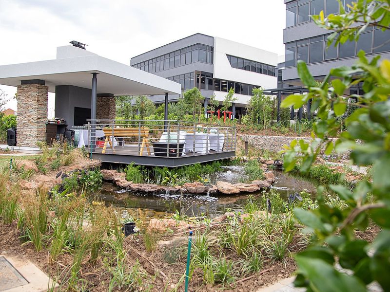 A modern covered patio area overlooking a landscaped garden with a decorative water feature and stone-clad structural elements.