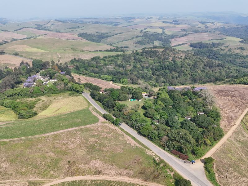 An expansive aerial view of the farm property, showcasing the surrounding landscape, rolling hills, and established vegetation.
