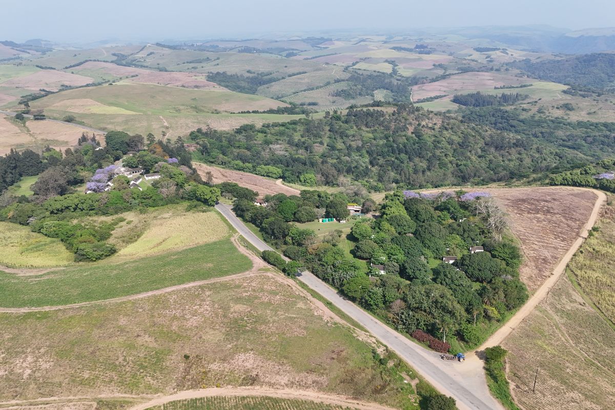 An expansive aerial view of the farm property, showcasing the surrounding landscape, rolling hills, and established vegetation.