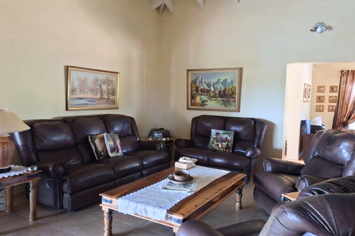 A spacious living room featuring high vaulted ceilings, neutral wall finishes, and durable tiled flooring, offering a comfortable and well-lit seating area.