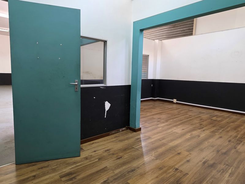 An empty office space featuring laminate flooring and a partitioned layout, suitable for commercial use with minor cosmetic updates required.
