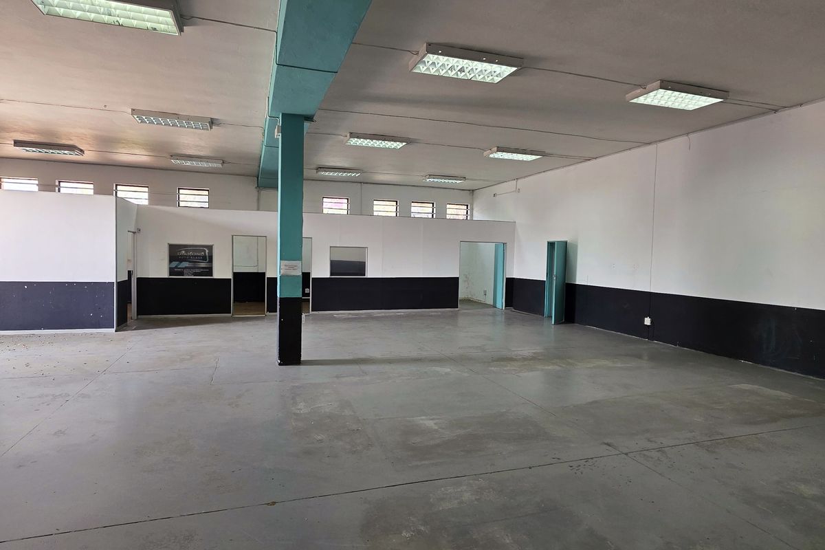 Spacious industrial utility area featuring concrete flooring, fluorescent lighting, and partitioned office space, suitable for workshop or storage use.