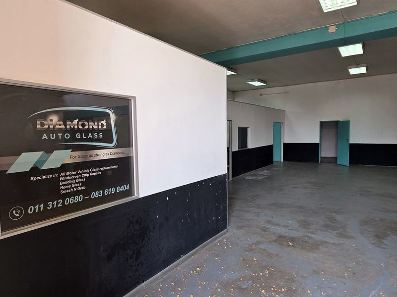 Spacious industrial utility area featuring painted concrete floors, structural columns, and recessed lighting, suitable for workshop or storage use.