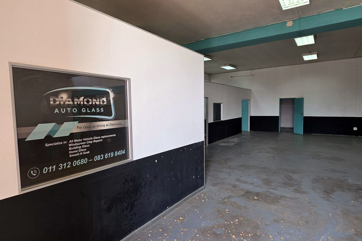 Spacious industrial utility area featuring painted concrete floors, structural columns, and recessed lighting, suitable for workshop or storage use.