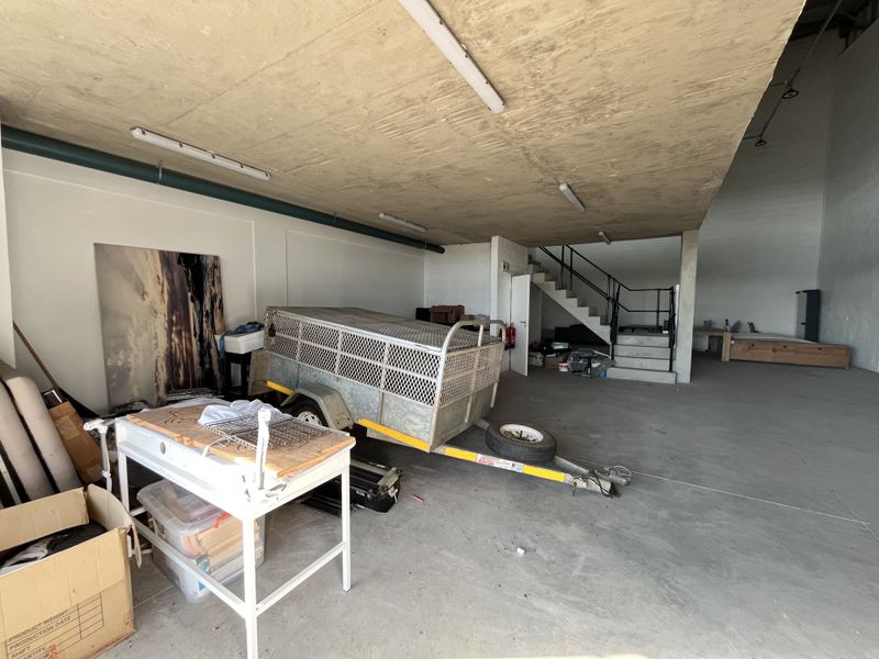 Spacious industrial warehouse unit featuring high concrete ceilings, polished concrete flooring, and an internal staircase leading to an elevated mezzanine level.