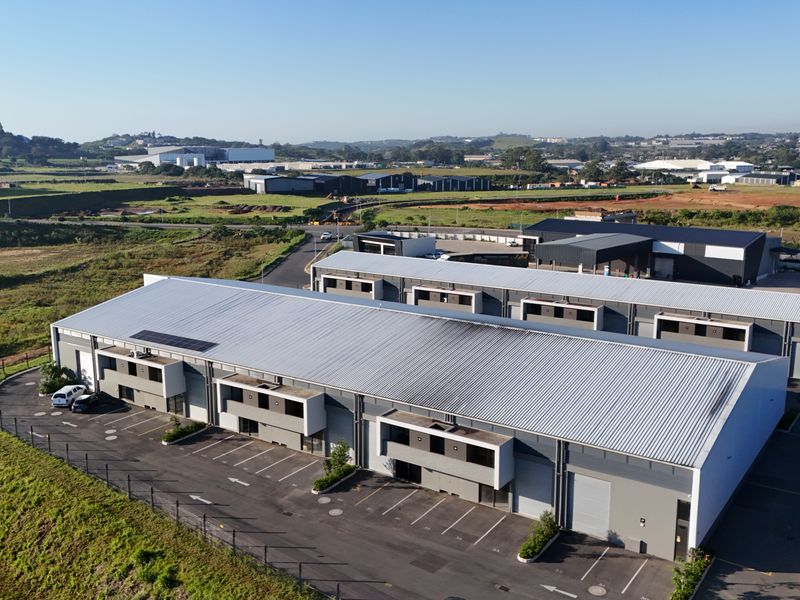 Aerial view of a modern industrial park featuring multiple warehouse units with roller shutter doors, paved parking areas, and perimeter fencing.