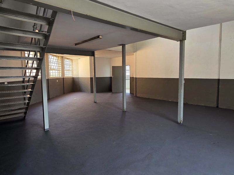 Spacious industrial open-plan area featuring a mezzanine level, steel staircase, and support columns, suitable for versatile commercial or workshop use.