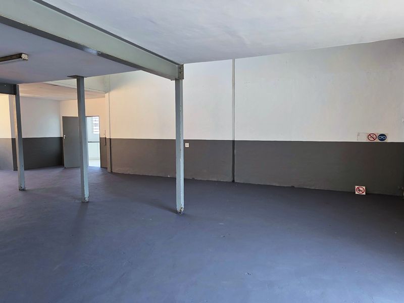 Spacious industrial utility area featuring a large yellow roller shutter door, steel support columns, and durable painted concrete flooring.