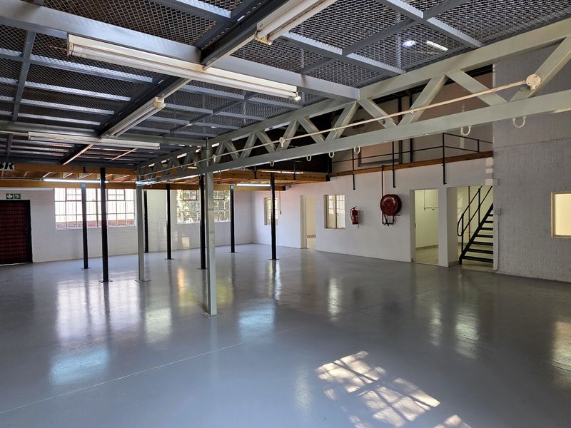 Spacious industrial utility area featuring high ceilings with exposed steel trusses, a mezzanine level, and durable epoxy-coated concrete flooring.