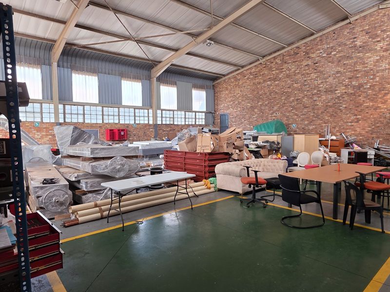 Spacious industrial utility area featuring exposed brick walls, high steel roof trusses, and painted concrete flooring with marked floor zones.
